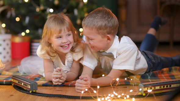 Happy children lie on the floor against the background of a festive Christmas tree