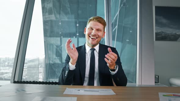 Young business man in a suit clapping at the camera