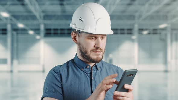 A Man Construction Worker with Helmet is Using Mobile Phone at Building Site alt