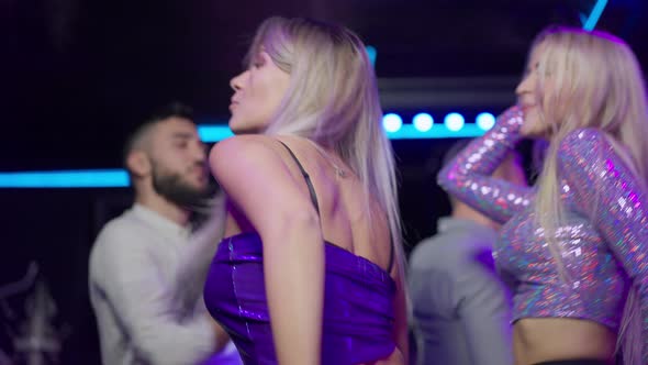 Side View of Slim Happy Young Woman Dancing in Night Club Singing Having Fun with Group of Friends