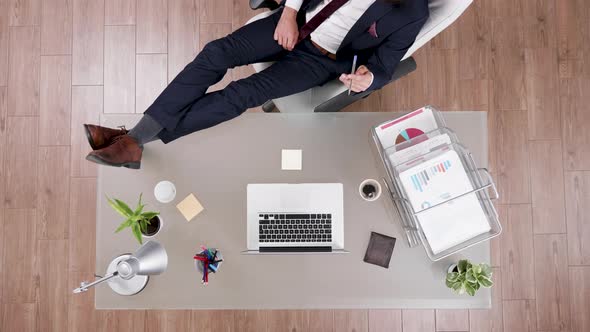 Top View of Businessman in Suit Staying Relaxed with Feet on His Office Desk