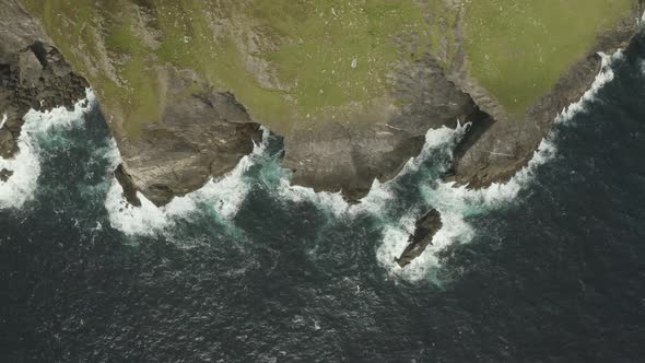 Slow cinematic aerial panning shot of the North Atlantic ocean breaking against the northern Irish c