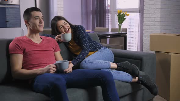 Couple Watching TV After Moving To New Flat