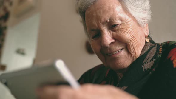 Aged woman with gadget sitting at table