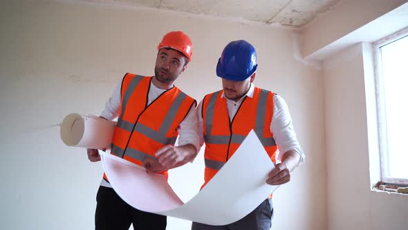 Men in Vests and Hardhats Inspecting and Discussing Blueprint While Working