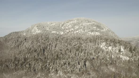 Flying up the slope of a snow covered mountain towards the peak AERIAL