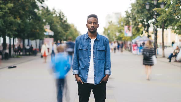 Zoom Out Time-lapse of Stressed African American Male Looking at Camera Standing in the Street in