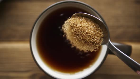 Pour Cane Sugar From Spoon Into Cup of Tea