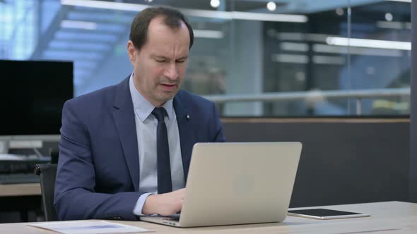 Businessman Having Back Pain While Using Laptop in Office