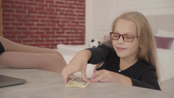 Close-up of a Happy Caucasian Teenage Girl Pushing Away Laptop and Scattering Money