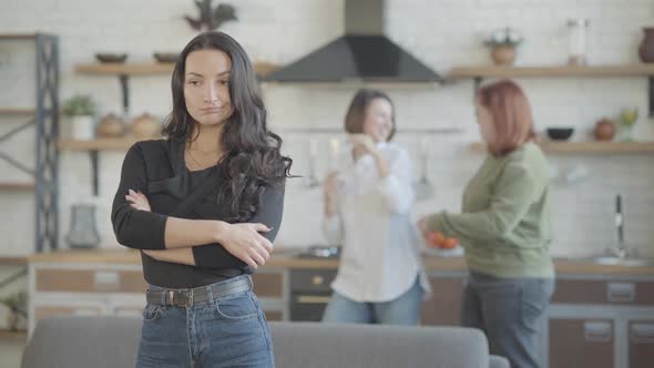 Upset Beautiful Woman Looking at Camera with Blurred Friends Dancing at Background