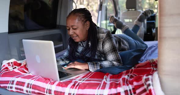 Mature african woman using computer laptop inside mini van camper