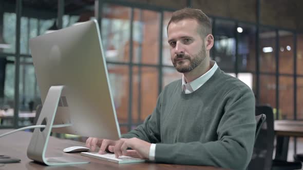 Smart Man Working on Computer and Showing Thumbs Down