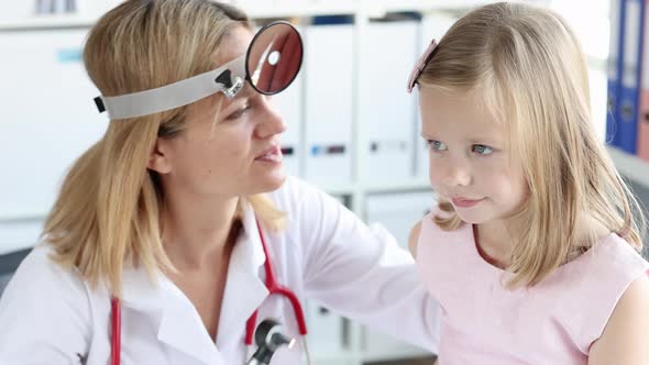 Otorhinolaryngologist Doctor with Frontal Reflector Examining Little Girl Ear with Otoscope  Movie