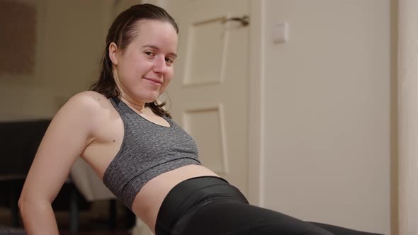 Home workout, young woman looking at the camera whilst holding stress positions.