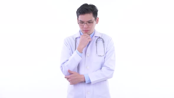 Stressed Young Asian Man Doctor Thinking and Looking Down