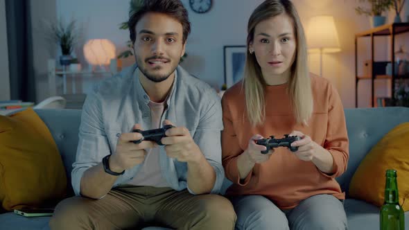 Happy Young Couple Playing Video Game Having Fun Together at Home at Night