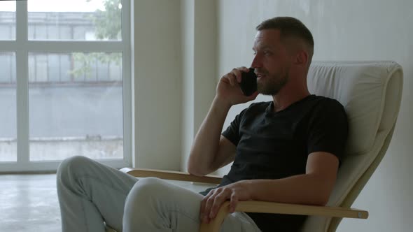 Footage Middleaged Man Talking on the Phone Smiling in Comfortable Chair