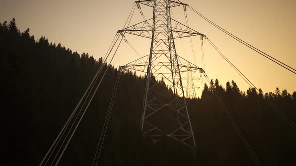 High voltage electricity pylons in a mountain forest during sunset. 4k