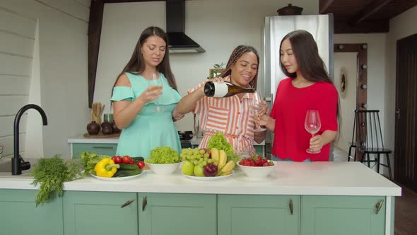 Multiracial Females Pouring Wine Clinking and Enjoying Party at Home