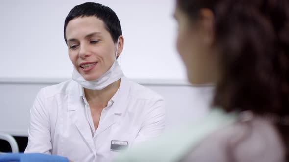 Cheerful Female Dentist in White Coat Talking to Patient