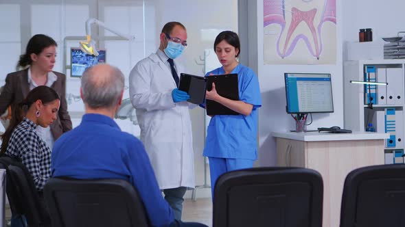 Dental Specialist Speaking with Assistant Standing in Waiting Room