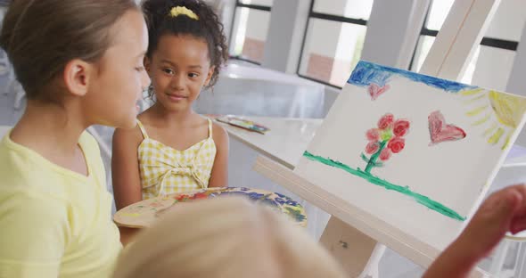 Video of happy diverse girls painting during art lessons at school