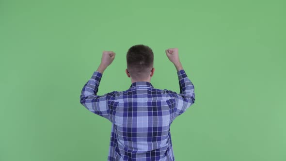 Rear View of Happy Young Hipster Man with Fists Raised