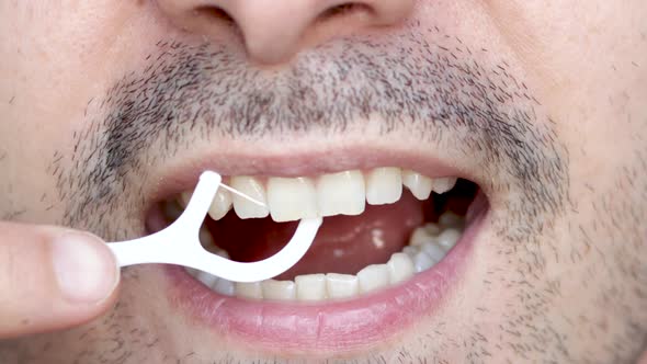close up4 k video man's mouth smiling and flossing his teeth with a white plastic toothpick. lips.na