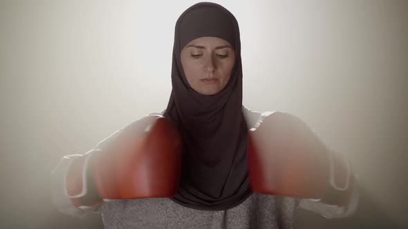 Portrait of Confident Muslim Sportswoman in Hijab Punching Fists in Boxing Gloves and Looking at