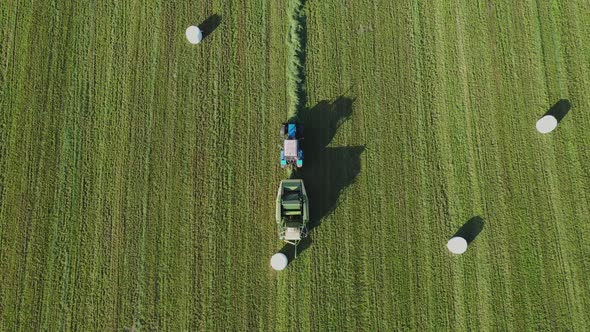 Farm Tractor Turns Rolls Of Hay And Wraps Them In White Package For Conservation