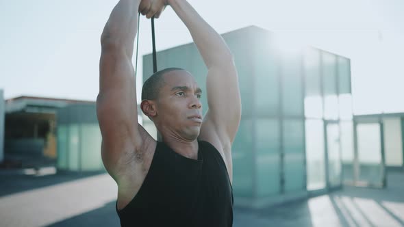 Serious sportsman wearing black T-shirt doing sport exercises with an elastic band