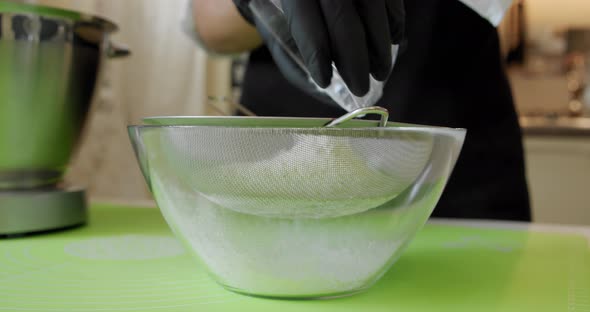 Woman Is Sifting Flour Through Sieve for Baking Mixing Ingredients in Metal Bowl, Close Up Slow
