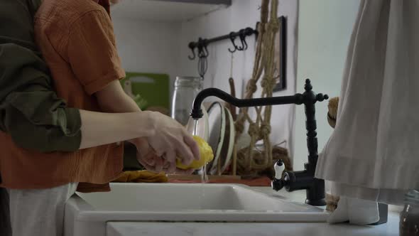 Little boy washing lemon with mother in kitchen