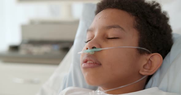 Close Up of Afroamerican Preteen Boy with Nasal Cannula Having Fever and Sleeping in Hospital Bed