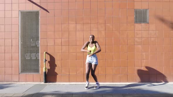 Young woman dancing in front of wall