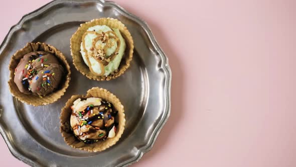 Waffle ice cream bowls with scoops of ice cream on a pink background.