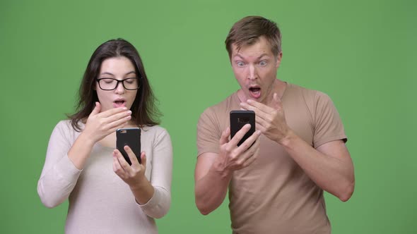 Young Couple Using Phone and Looking Shocked Together