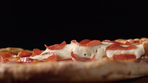 A slice of pizza being picked up out of a whole pizza. Slow Motion.