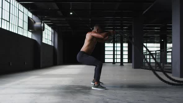 African american man exercising battling ropes in an empty urban building