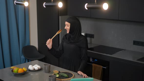 Joyful Beautiful Middle Eastern Woman Having Fun Cooking Healthful Salad in Kitchen at Home