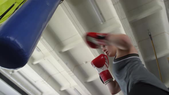 Energetic Sportswoman Punching Heavy Bag during Boxing Workout