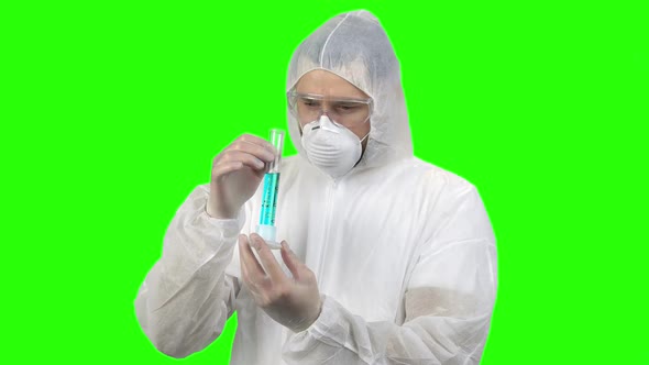 Man in Respiratory and Protective Clothing Holding Test Tube with Blue Liquid