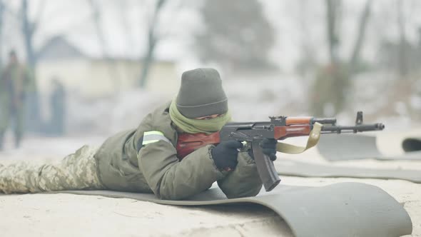 Serious Confident Female Soldier Lying on Polygon Shooting in Slow Motion From Rifled Army Gun