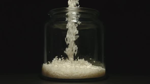 SLOW MOTION: White Rice Grains Pouring Into A Glass Jar