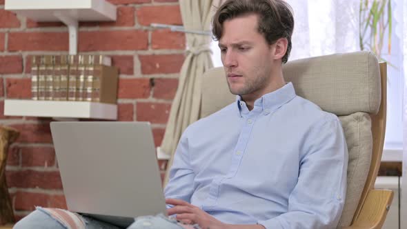 Young Man Celebrating Success on Laptop