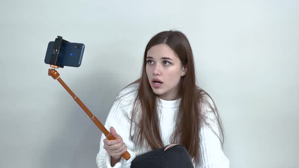 Caucasian Girl Is Sitting on Floor Holding Cellphone Unsure of Something Closeup