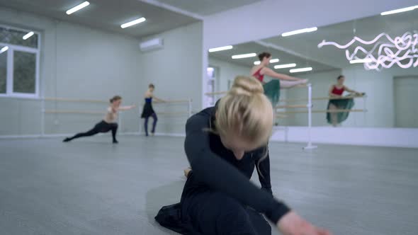 Young Slim Blond Caucasian Ballerina in Twine Pose Bending Moving Rehearsing with People in Dance
