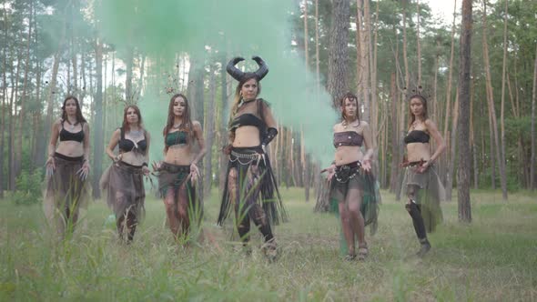 Group of Women Dancers with Make-up and in Mystical Fabulous Costumes Dancing in Color Smoke. Forest