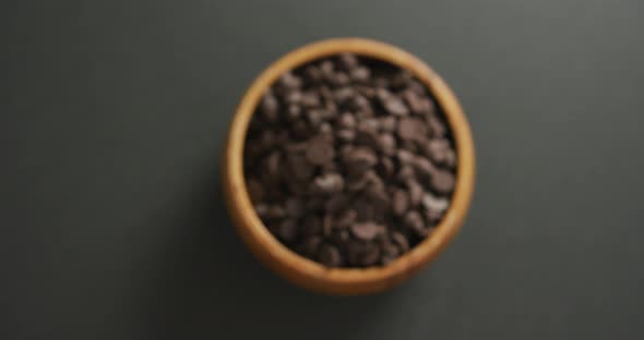 Video of overhead view of wooden bowl of chocolate chip over grey background